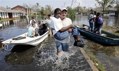 A rescuer carries a young man who is unable to walk through the water to safety.