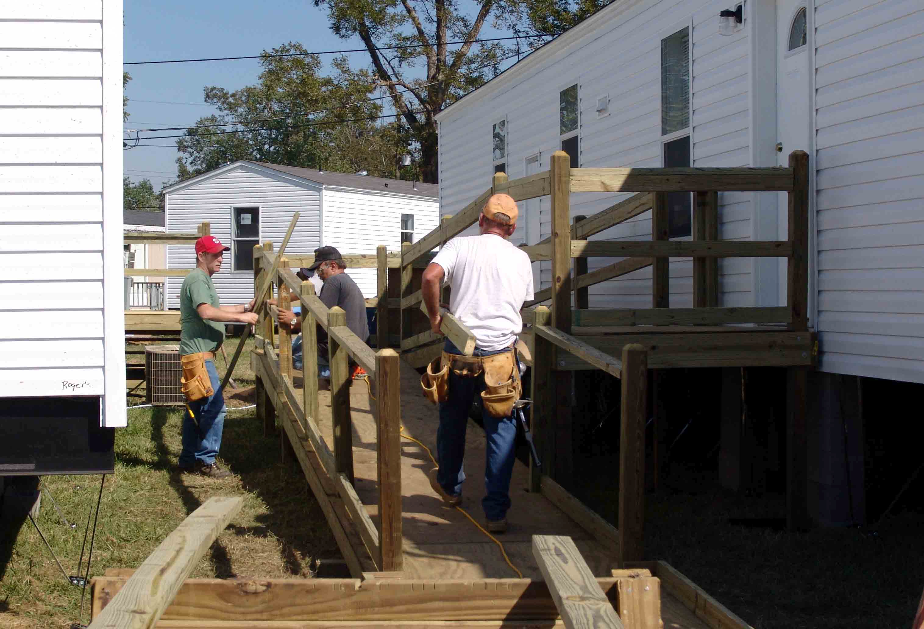 Workers build a ramp to create a wheelchair accessible mobile home.