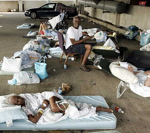 Photo of elderly African Americans resting on mattresses in a parking garage/shelter.