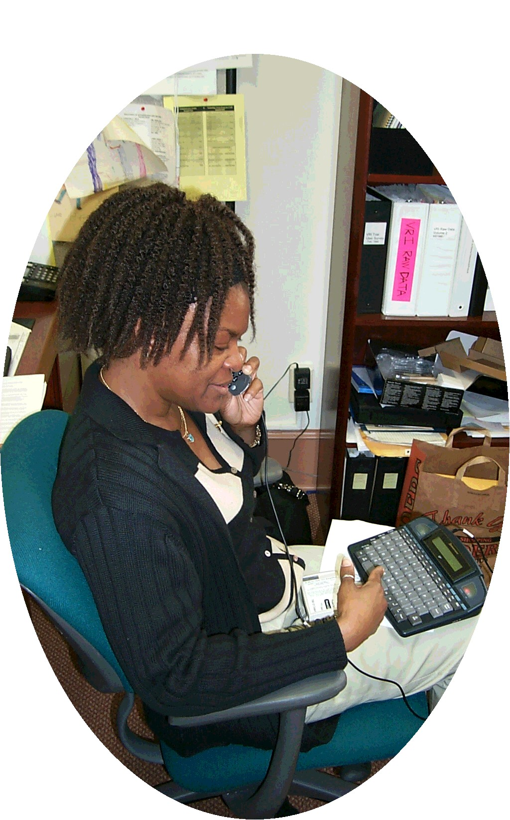 Image of a woman using a cell phone connected to a TTY.