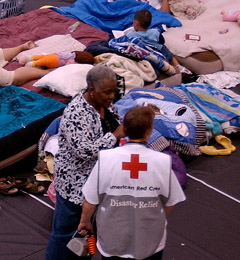 Photo of Red Cross Relief Worker helping in a room filled with cots.