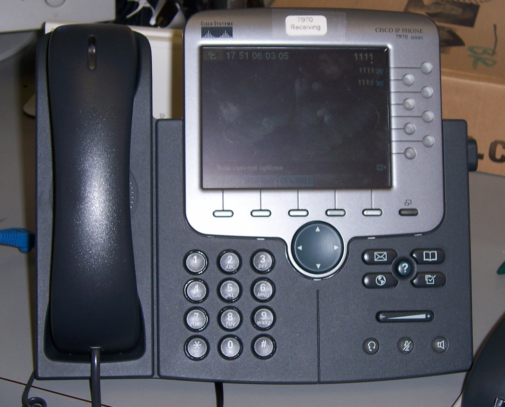 Image of a VoIP phone. It looks like a typical phone with a handset and buttons, but also has a screen.