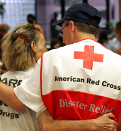 Photo of male Red Cross worker hugging a female evacuee.